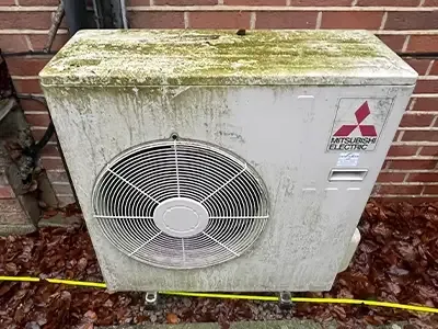 Outdoor heat pump unit with moss on the top before cleaning
