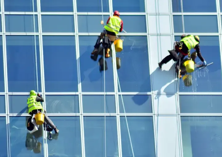 Rope access team abseiling down a glass building to clean the windows