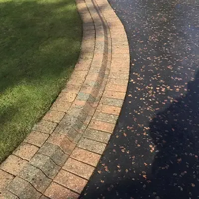 Clean block paving edge beside a tarmac driveway