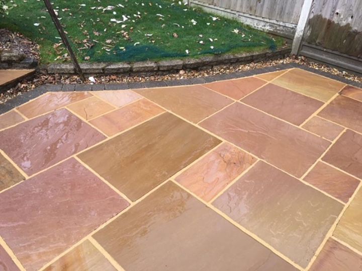 Clean sandstone patio with a lawn behind