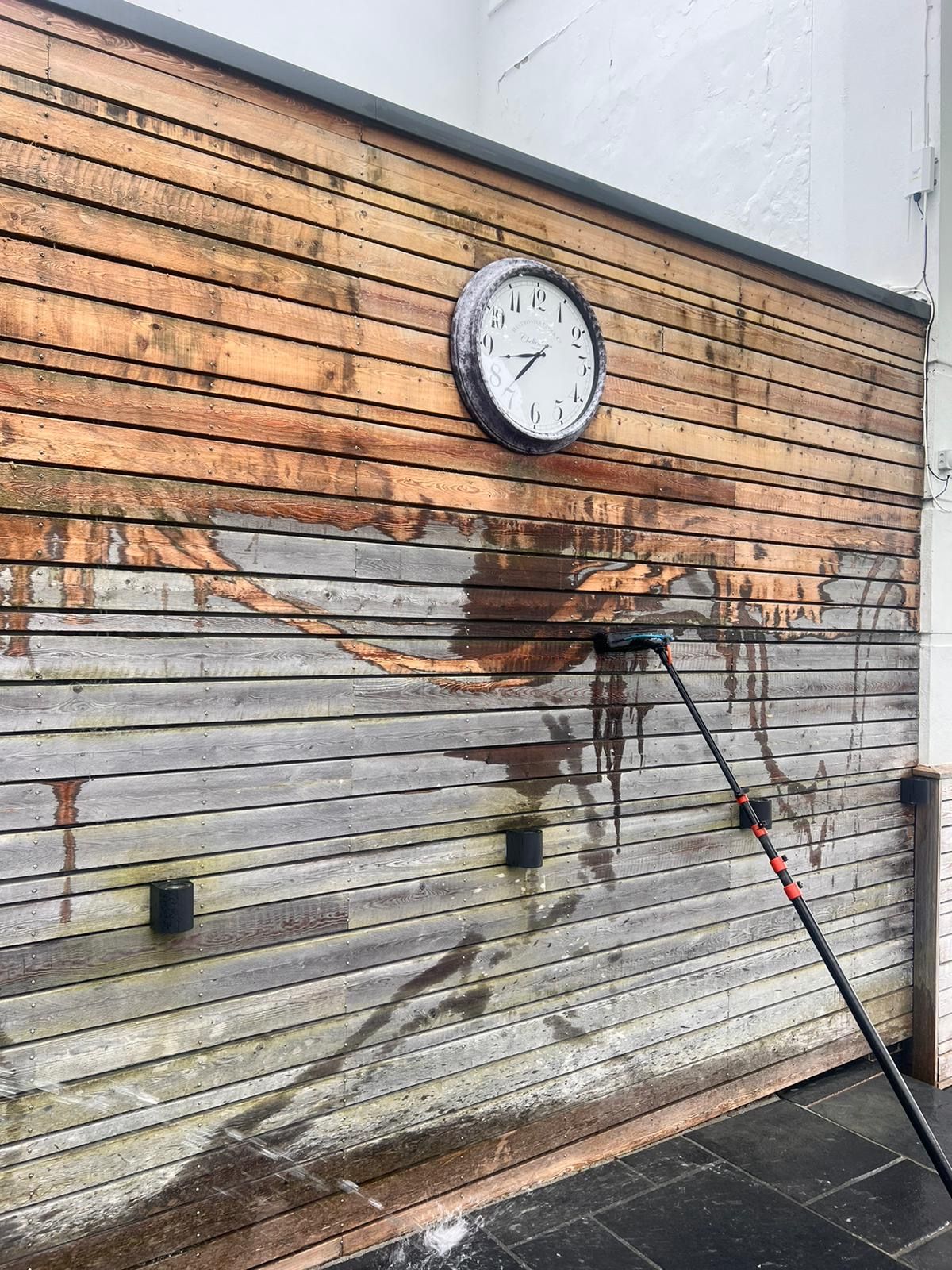 Timber cladding part-way through cleaning, showing stains being lifted