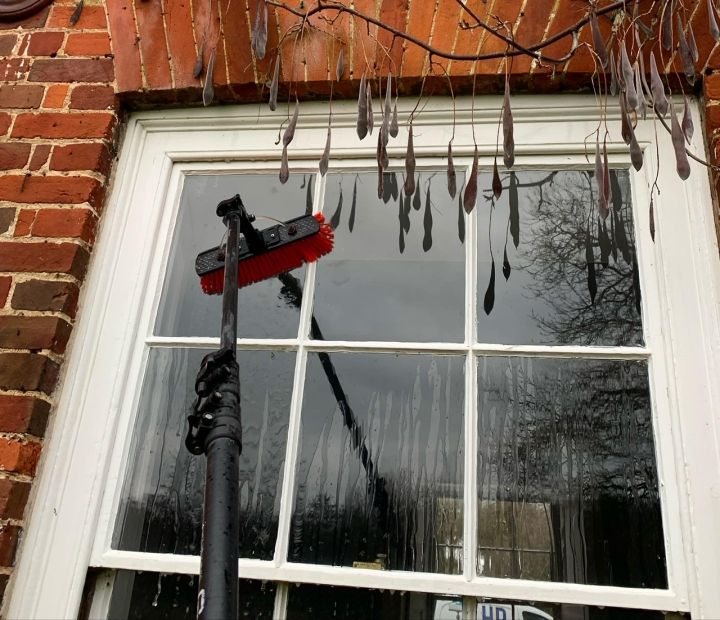 Water-fed pole brush cleaning a white sash window